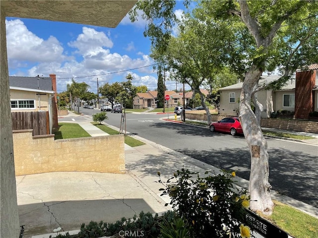 view of road with curbs, sidewalks, traffic signs, and a residential view