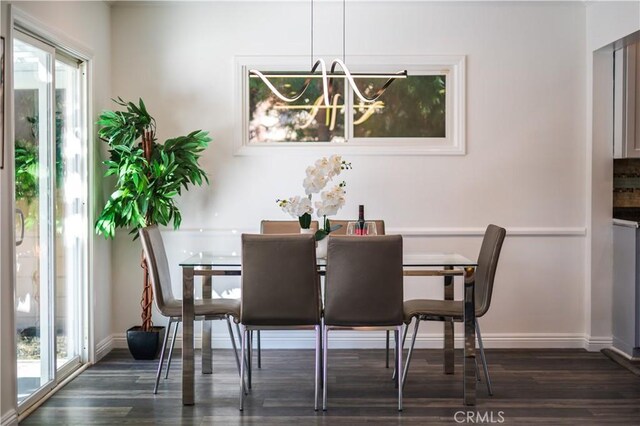 dining area featuring a notable chandelier, baseboards, and dark wood-type flooring