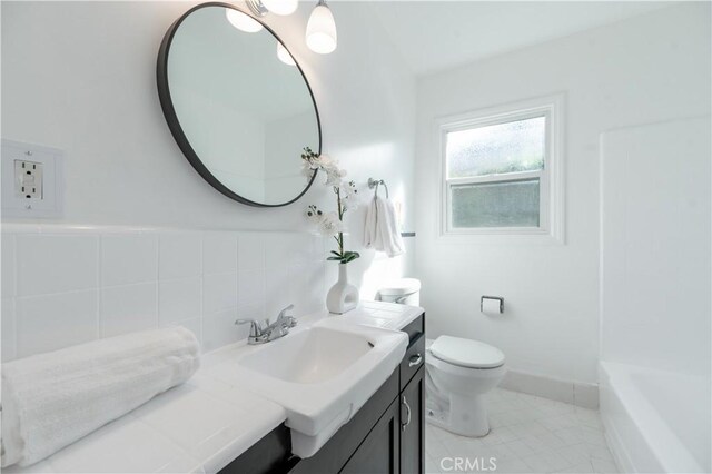 bathroom with tile patterned flooring, tile walls, vanity, and toilet