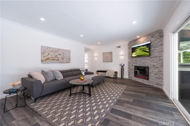 living area featuring a stone fireplace, recessed lighting, dark wood finished floors, and crown molding