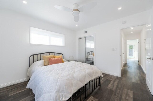 bedroom with dark wood-style floors, multiple windows, and baseboards