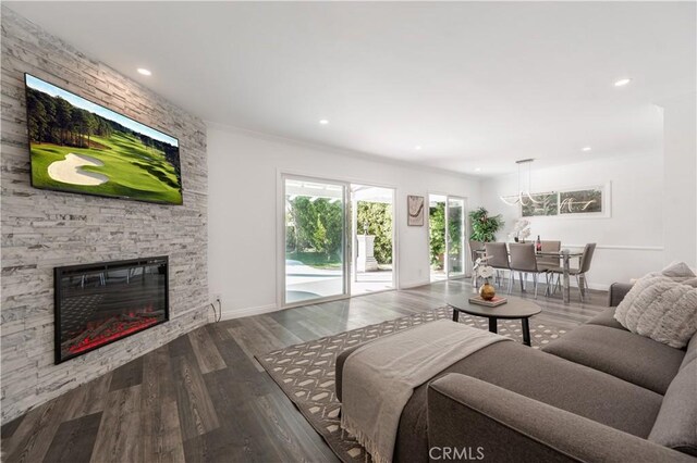 living room with dark wood-style floors, recessed lighting, a stone fireplace, and baseboards