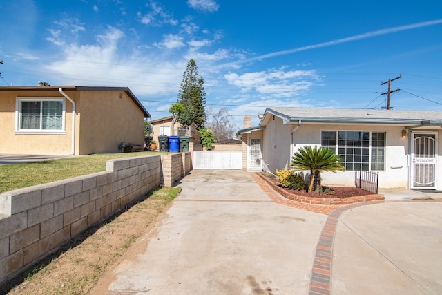 view of side of home featuring driveway, fence, and stucco siding