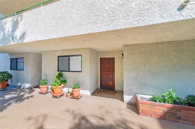 view of exterior entry with a patio area and stucco siding