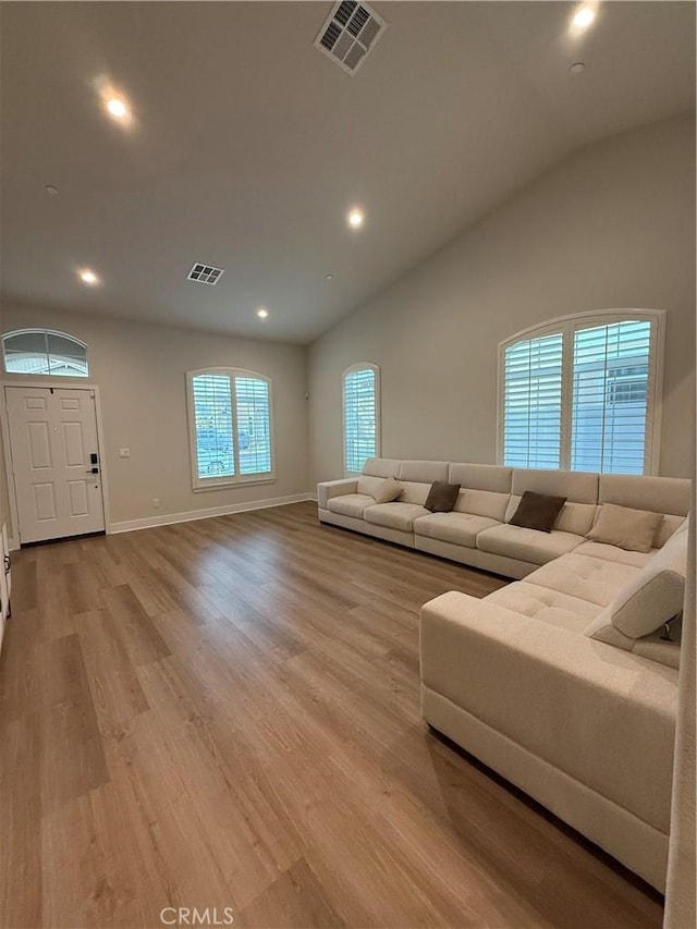 living room with lofted ceiling, light wood-style flooring, and visible vents