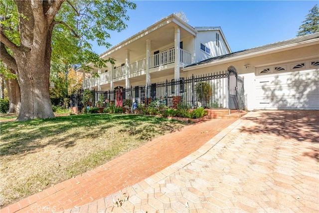 front facade with fence, a garage, driveway, and stucco siding