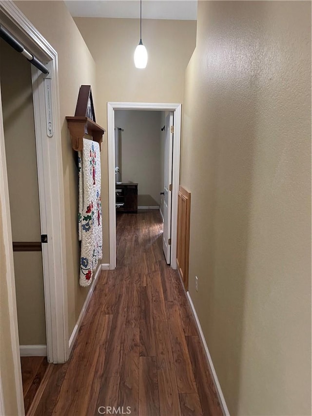 hallway featuring dark wood-type flooring and baseboards