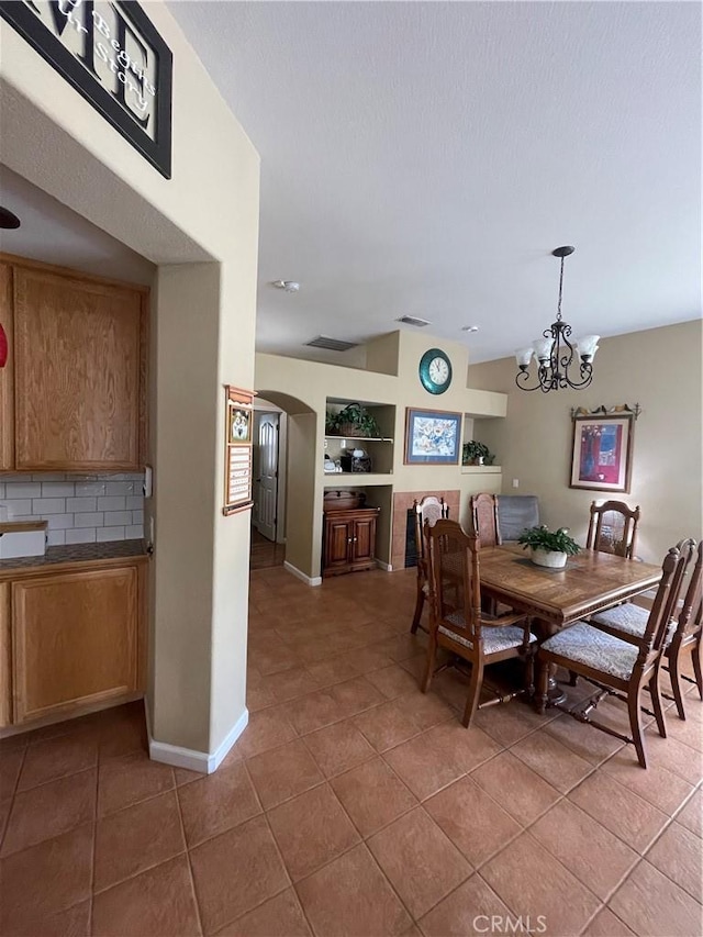 tiled dining space featuring a chandelier, arched walkways, and baseboards