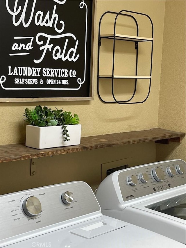 clothes washing area featuring a textured wall, laundry area, and separate washer and dryer