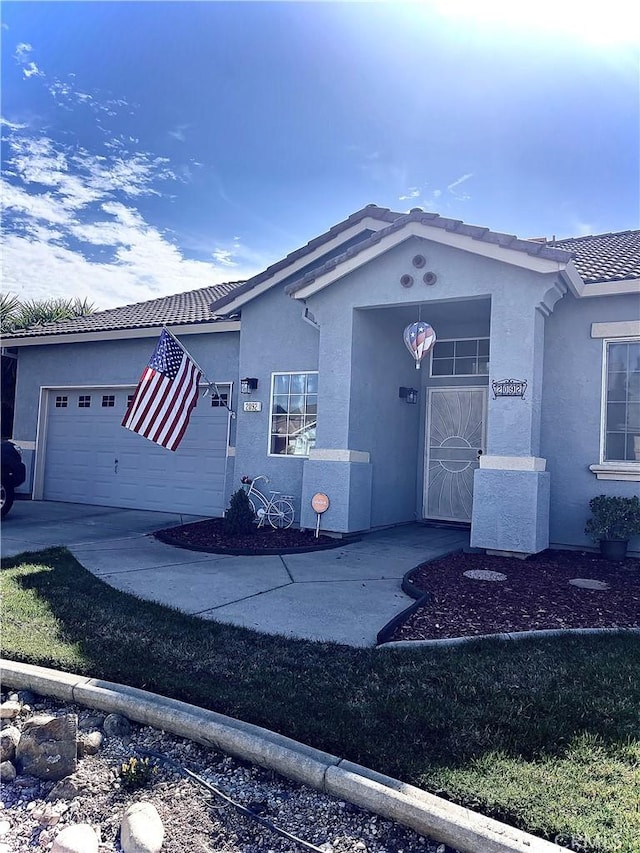 view of front of property featuring a tile roof, an attached garage, and stucco siding