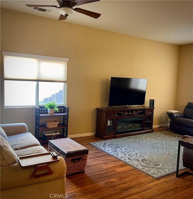 living area featuring ceiling fan, wood finished floors, visible vents, and baseboards