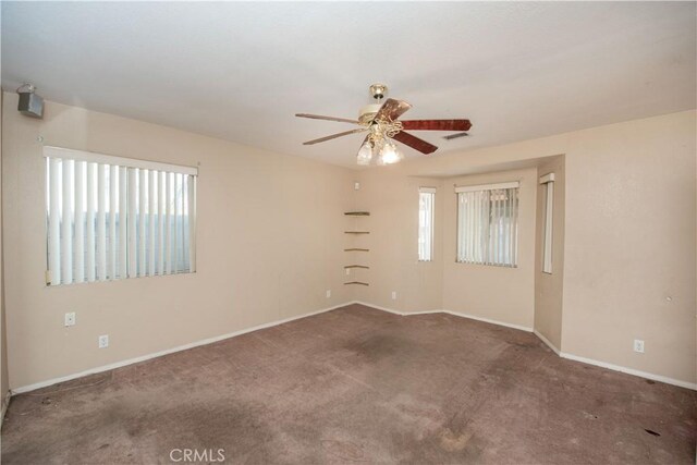 spare room featuring a ceiling fan, dark colored carpet, visible vents, and baseboards