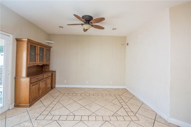 empty room with light tile patterned floors, ceiling fan, and baseboards