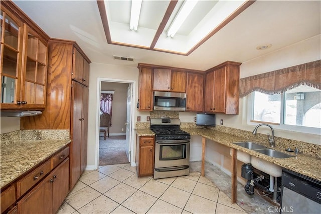 kitchen with stainless steel appliances, light stone counters, a sink, and visible vents