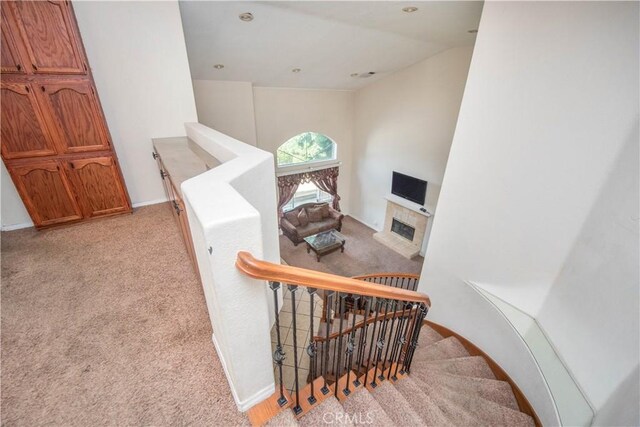 staircase with lofted ceiling, carpet, a tile fireplace, and baseboards