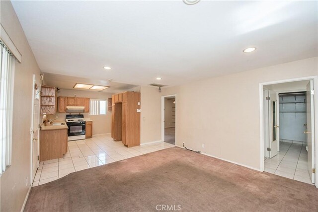 kitchen with white range, light tile patterned floors, light countertops, light carpet, and a sink