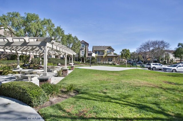 view of property's community with community basketball court, a residential view, a lawn, and a pergola