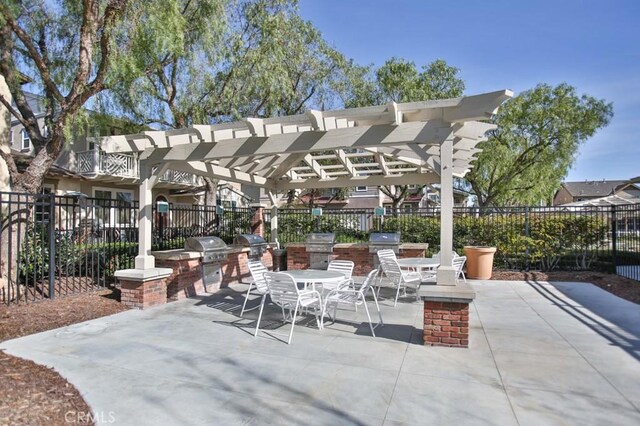 view of patio featuring exterior kitchen, outdoor dining area, fence, and a pergola