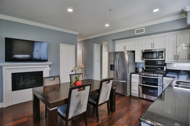 kitchen featuring stainless steel appliances, dark countertops, visible vents, dark wood-type flooring, and white cabinetry