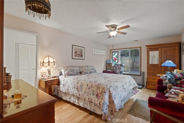 bedroom featuring a textured ceiling, light wood finished floors, and a ceiling fan