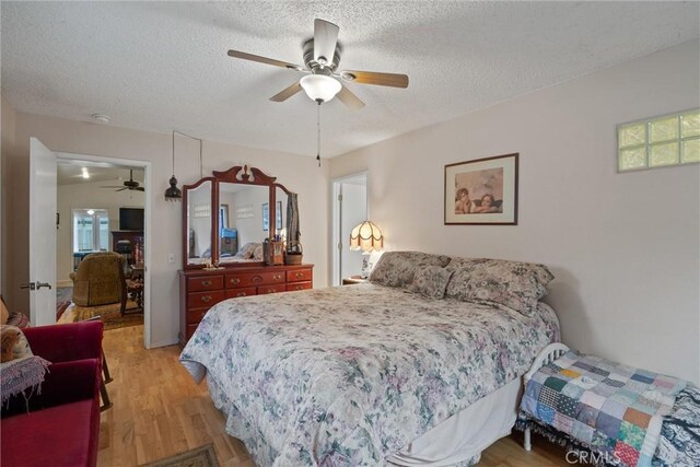 bedroom with light wood-type flooring, ceiling fan, and a textured ceiling