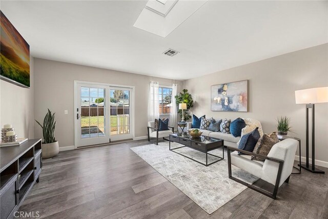 living area featuring a skylight, baseboards, visible vents, and dark wood finished floors