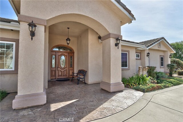 property entrance with a tile roof and stucco siding