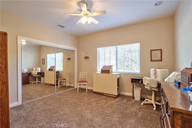 carpeted home office featuring a wealth of natural light, visible vents, ceiling fan, and baseboards