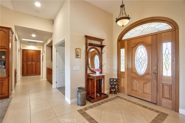 entrance foyer with light tile patterned flooring, a towering ceiling, and baseboards