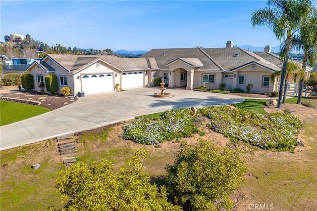 view of front of home featuring a garage, driveway, a tile roof, a chimney, and stucco siding