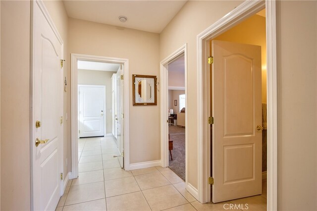 corridor featuring baseboards and light tile patterned floors