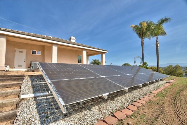 exterior space with ground mounted solar panels and stucco siding