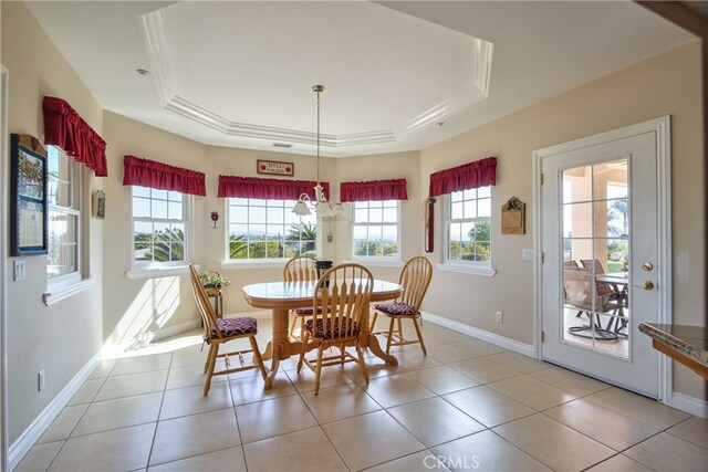 dining room featuring a tray ceiling, light tile patterned flooring, and baseboards