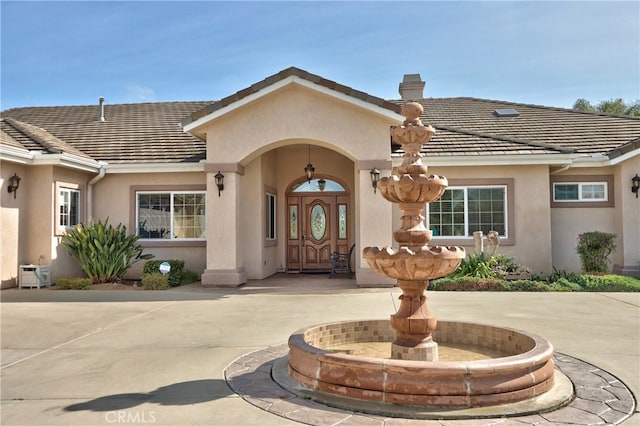 property entrance featuring a tile roof, a chimney, and stucco siding