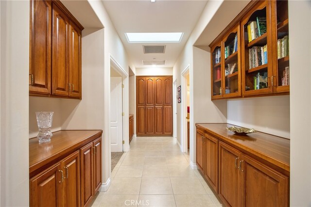 hallway featuring light tile patterned flooring, visible vents, and baseboards