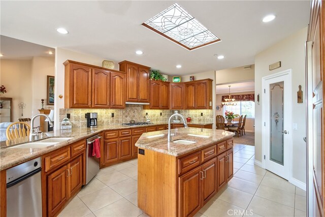 kitchen with light stone counters, brown cabinets, a sink, and an island with sink