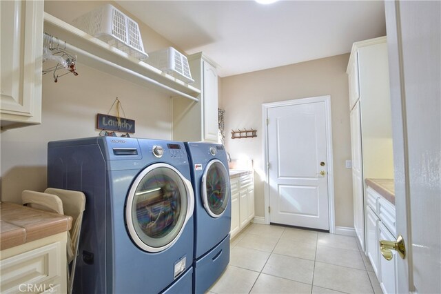 laundry room featuring cabinet space, light tile patterned floors, baseboards, and washer and dryer