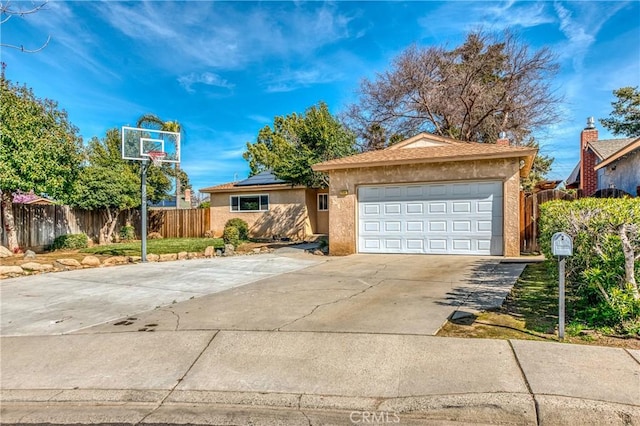 view of front of home featuring driveway, an attached garage, fence, and stucco siding