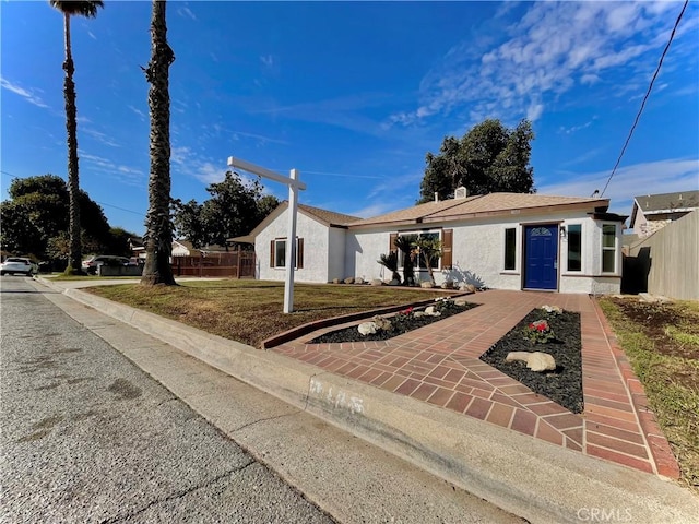 ranch-style home with fence, a front lawn, and stucco siding