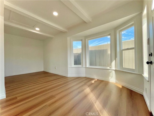 spare room with beam ceiling, recessed lighting, light wood-style flooring, attic access, and baseboards