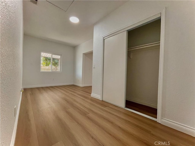 unfurnished bedroom featuring light wood-type flooring, baseboards, and a textured wall