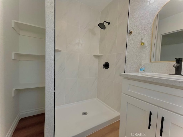 full bathroom featuring a stall shower, baseboards, a textured wall, and vanity