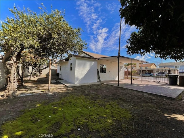 rear view of property featuring a lawn, a patio area, fence, and stucco siding