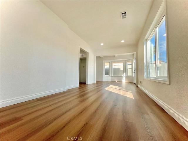 empty room with a textured wall, recessed lighting, wood finished floors, visible vents, and baseboards