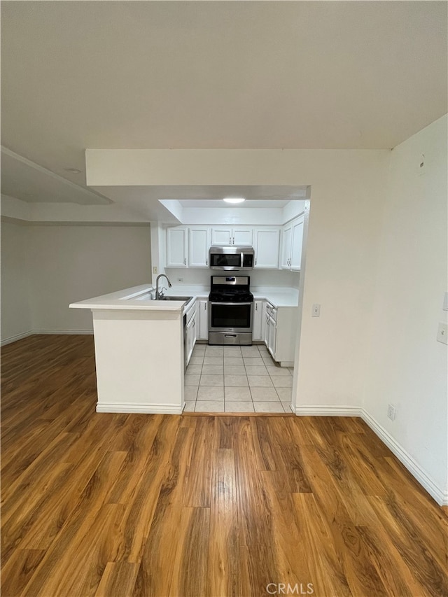 10115 Pinewood Ave Unit 102, Tujunga, CA 91042 - kitchen featuring stainless steel appliances, a peninsula, light countertops, light wood-type flooring, and white cabinets