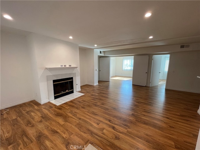 unfurnished living room featuring recessed lighting, visible vents, wood finished floors, and a tiled fireplace