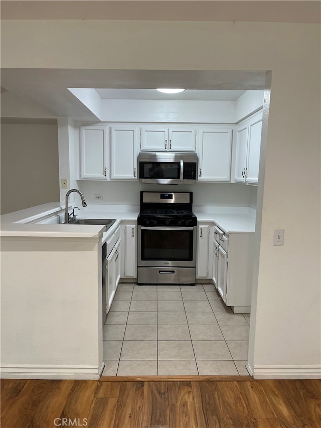 kitchen with stainless steel appliances, white cabinets, light countertops, and a peninsula