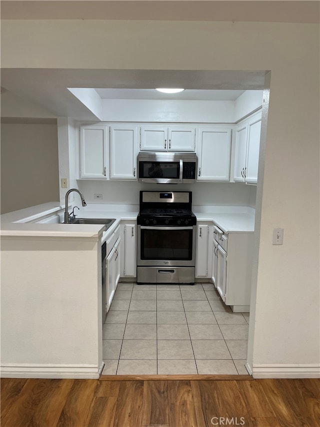 10115 Pinewood Ave Unit 102, Tujunga, CA 91042 - kitchen with stainless steel appliances, a peninsula, light countertops, and white cabinets