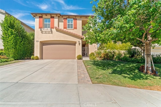 mediterranean / spanish-style home featuring concrete driveway, stucco siding, a tile roof, an attached garage, and a front yard