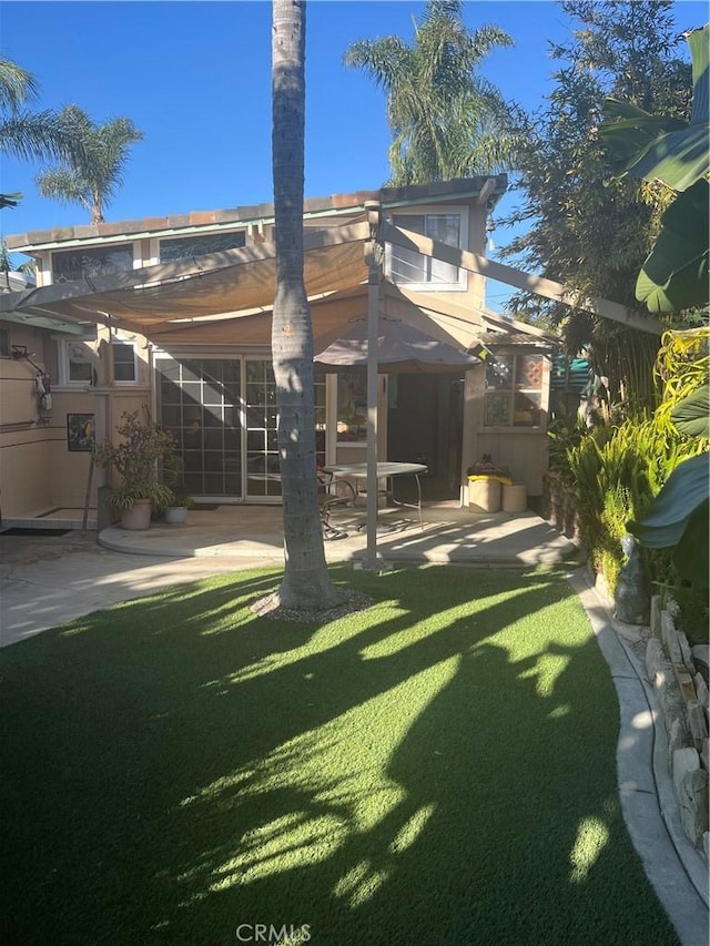 back of property featuring stucco siding, a lawn, and a patio